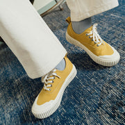 Women's Sato Oxford in Dijon canvas, close-up worn with white pants on a blue rug