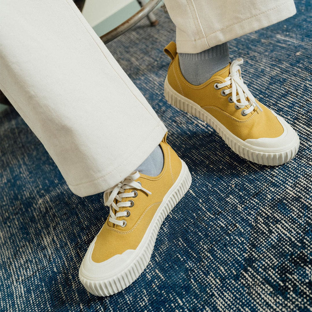 Women's Sato Oxford in Dijon canvas, close-up worn with white pants on a blue rug