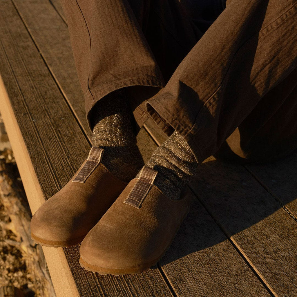 Men's Tiburon Trekker sandal in Fossil leather, close-up worn with brown pants on a wood deck