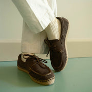 Men's Carmel Loafer in Dark Chocolate suede, worn with white pants and socks on a pale green floor