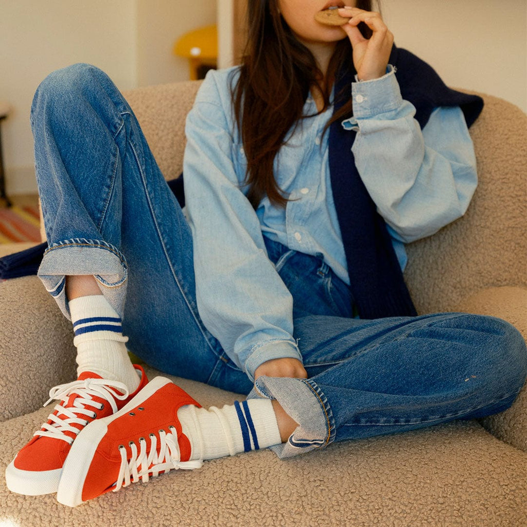 Women's Monterey Sneaker in Forever Red canvas, worn by a woman seated on a shearling sofa