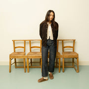 Women's Tiburon Trekker sandal in Elmwood leather, worn by a woman standing in front of wooden chairs