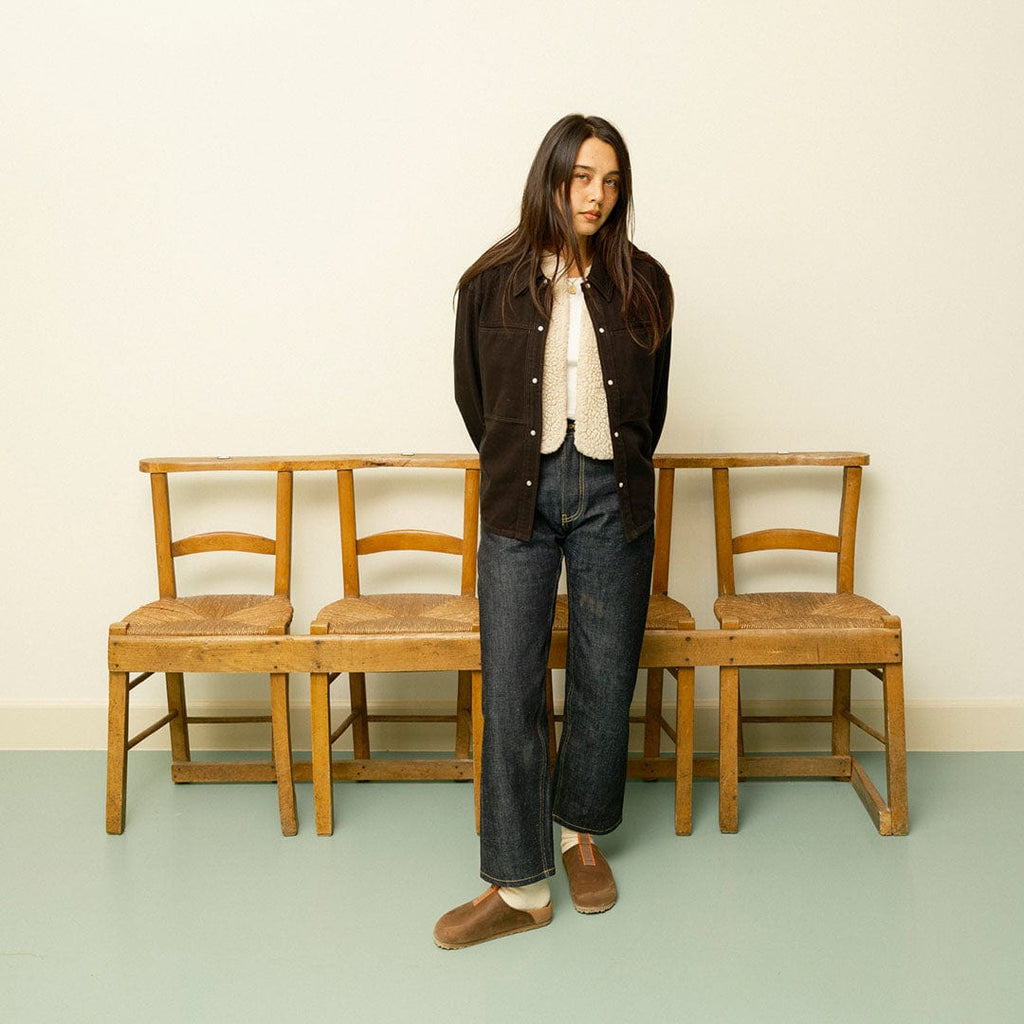 Women's Tiburon Trekker sandal in Elmwood leather, worn by a woman standing in front of wooden chairs
