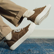 Men's Sato Oxford in Brownstone canvas, worn with khaki pants on a blue rug, side view