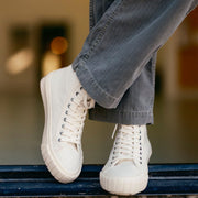 Men's La Brea Lug in White canvas, worn with gray cuffed pants, one foot raised