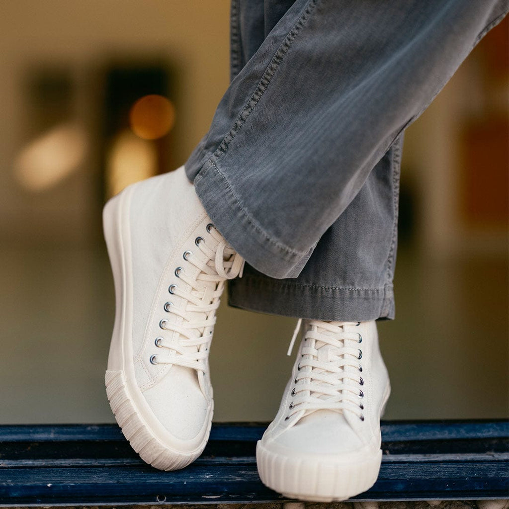 Men's La Brea Lug in White canvas, worn with gray cuffed pants, one foot raised