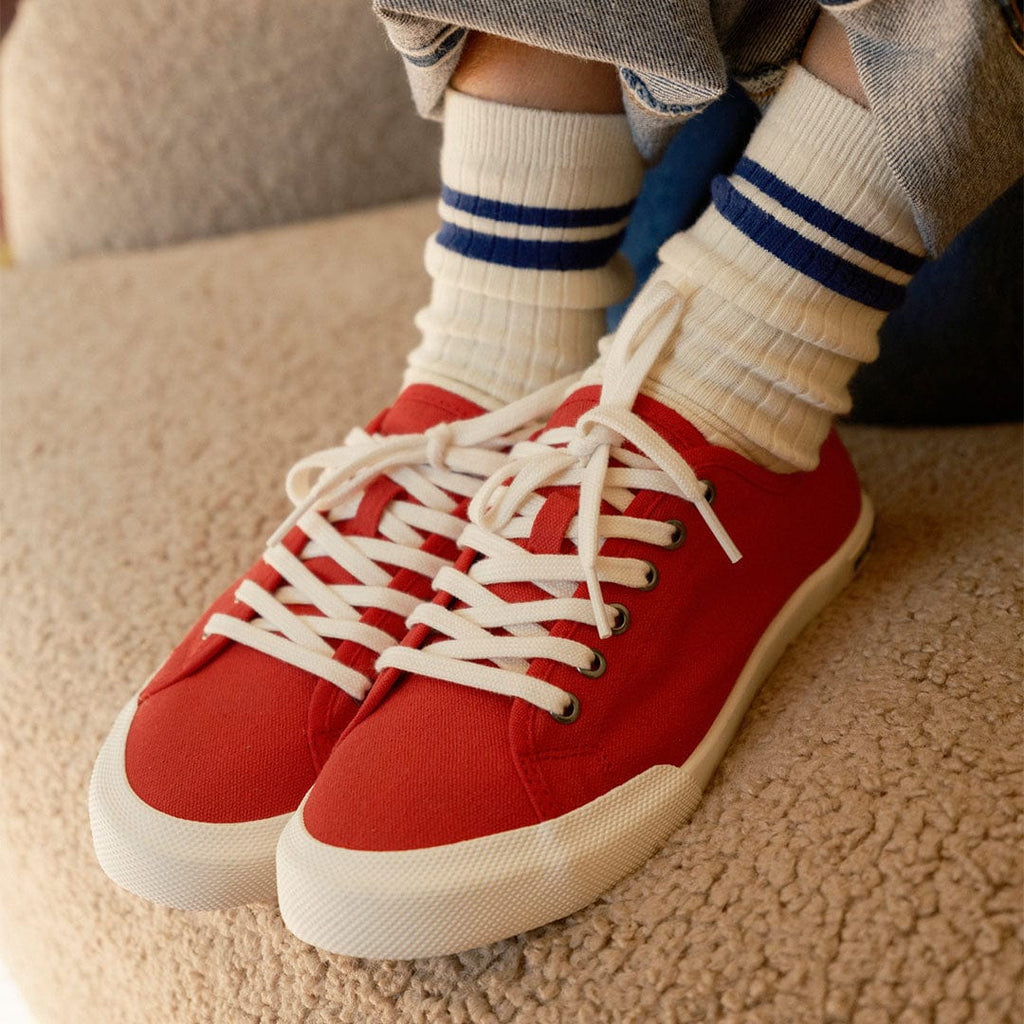 Women's Monterey Sneaker in Forever Red canvas, worn with striped socks on a shearling seat, front view