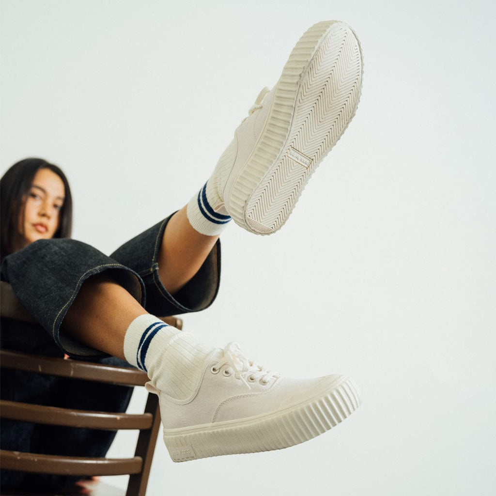 Women's Sato Oxford in Parchment canvas, worn with striped socks, sole raised toward the camera