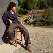 Men's Sun-tans Buck in Timber leather, worn by a man seated on a wooden chair outdoors