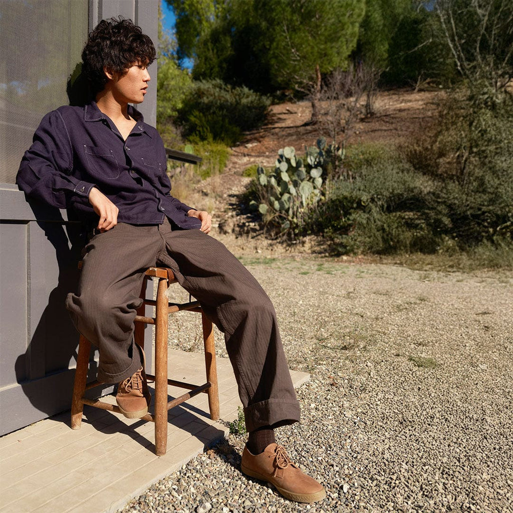 Men's Sun-tans Buck in Timber leather, worn by a man seated on a wooden chair outdoors