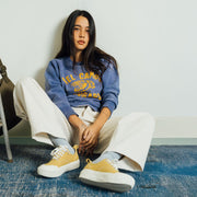 Women's Sato Oxford in Dijon canvas, worn by a woman seated against a white wall