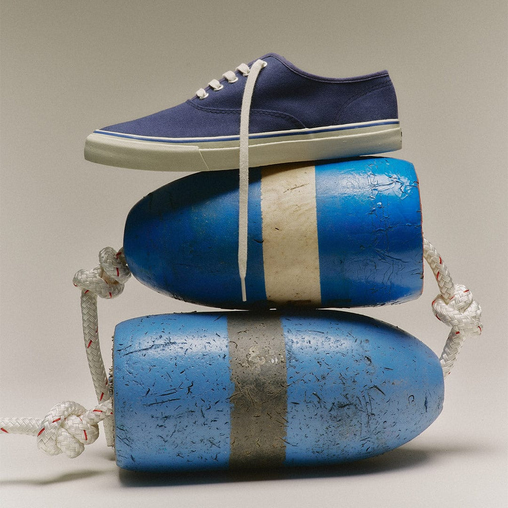 Men's Founders Edition Yacht Shoe in Navy canvas, resting on two blue and white buoys