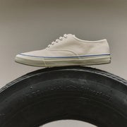 Women's Founders Edition Yacht Shoe in White canvas, side view resting on a tire