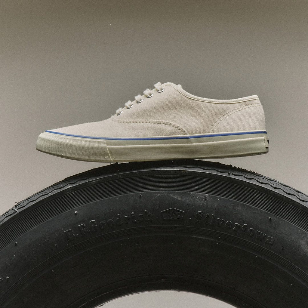 Women's Founders Edition Yacht Shoe in White canvas, side view resting on a tire