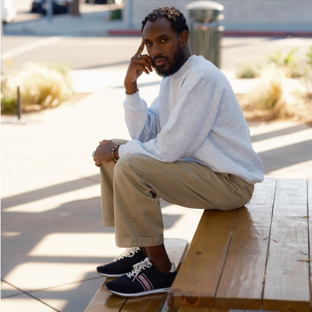 Men's Royal Runner sneaker in Black nylon and suede, worn with khaki pants by a person seated on a wooden bench