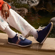 Men's Royal Runner sneaker in Blue nylon and suede, close-up worn with paint-splattered white pants on a wooden ledge