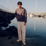 Men's Baja Slip On in Cloud vegan nubuck, worn by a person standing at a marina in a gray sweatshirt