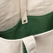 Inside view of a natural canvas tote bag with green lining and snap