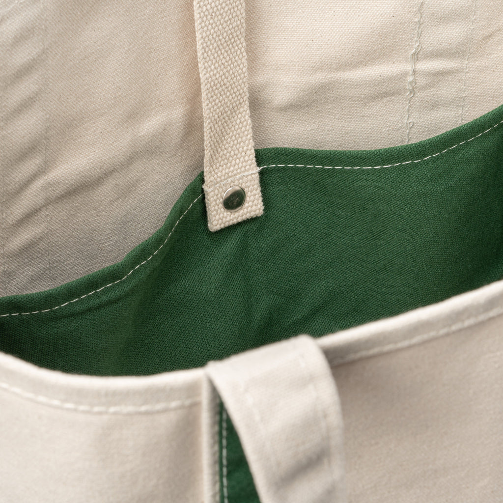 Inside view of a natural canvas tote bag with green lining and snap