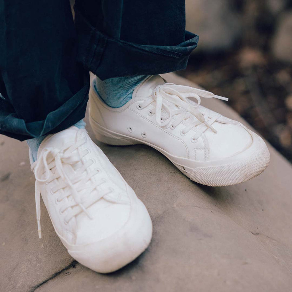 Women's SeaChange LTT sneaker in White Corn Leather, close-up worn with teal socks on a rock ledge
