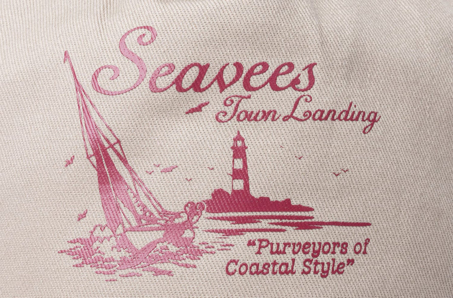 Close up of the pink Town's Landing lighthouse embroidery on a khaki hat