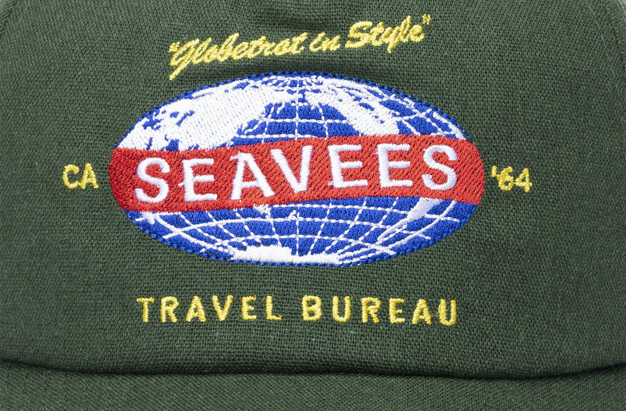 Close up of the SeaVees Travel Bureau globe patch on a green hat
