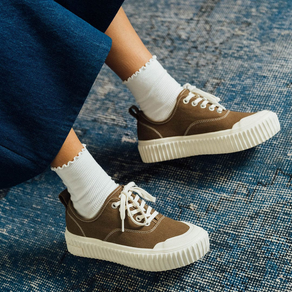 Women's Sato Oxford in Brownstone canvas, worn with white socks on a blue rug, side view