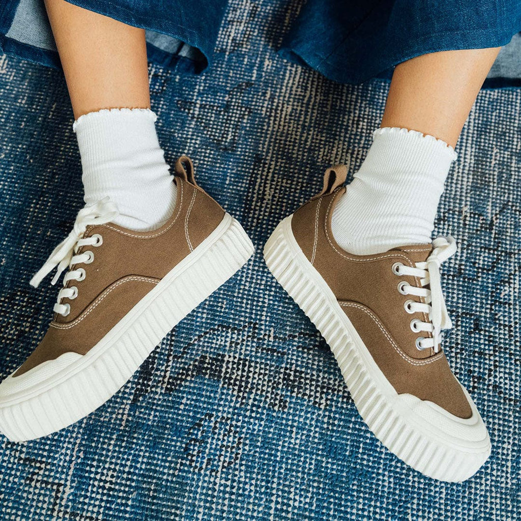 Women's Sato Oxford in Brownstone canvas, pair worn with white socks on a blue rug, front view