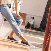 Women's Hawthorne Slip On in True Navy fabric, worn with cuffed jeans while walking up steps