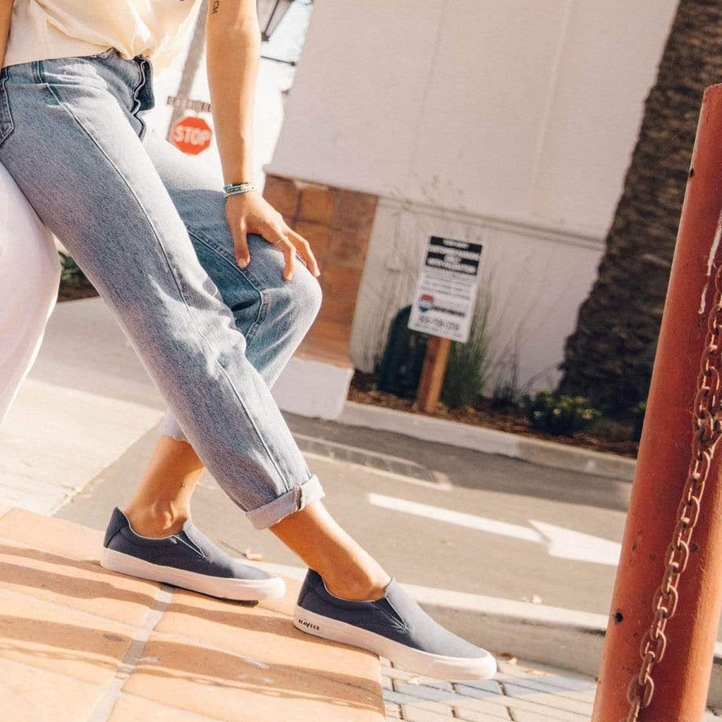 Women's Hawthorne Slip On in True Navy fabric, worn with cuffed jeans while walking up steps