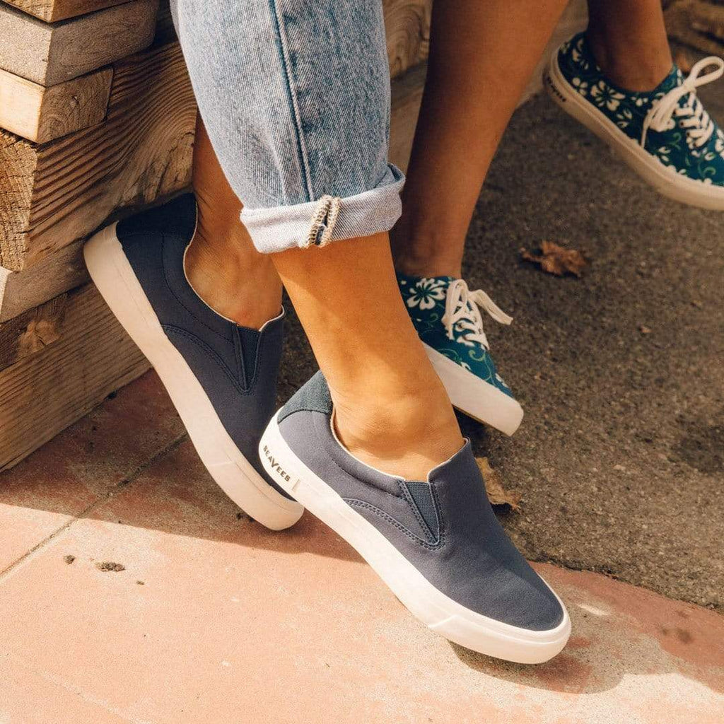 Women's Hawthorne Slip On in True Navy fabric, worn with cuffed jeans on a sunny patio