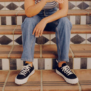 Women's Melrose Lug Platform in Black canvas, worn with jeans by a person seated on tiled stairs