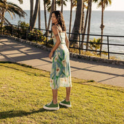 Women's Monterey Sneaker in Cactus canvas, worn with a printed dress, full-length view on a grassy cliffside path