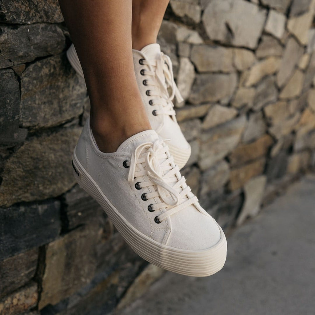 Women's Monterey Sneaker in Bleach canvas, close-up worn against a stone wall