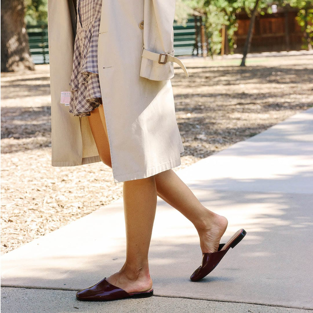 Women's Sadie Slide in Deep Cherry rubber, worn with a long coat, walking on a sidewalk