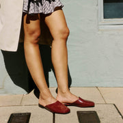 Women's Sadie Slide in Deep Cherry rubber, worn with a dark skirt on a tile patio