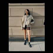 Women's Salt Creek Boot in Black leather, worn by a person standing against a stone wall in a tan jacket