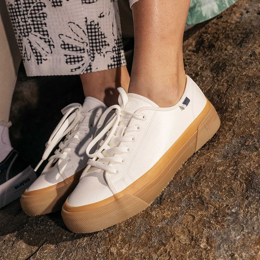 Women's SeaChange LTT sneaker in White/Gum corn leather, close-up worn with printed pants and bare ankles, gum sole visible