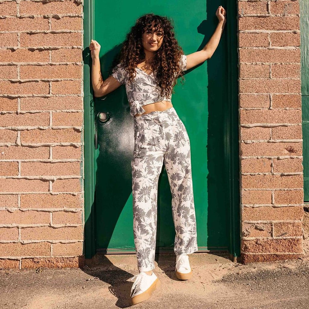 Women's SeaChange LTT sneaker in White/Gum corn leather, worn with printed pants, full-length view in front of a green door