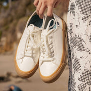 Women's SeaChange LTT sneaker in White/Gum corn leather, pair held in hand, gum soles visible