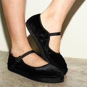 Women's Carlyle Mary Jane in Black velvet, worn with a strap closure on a concrete floor, close up