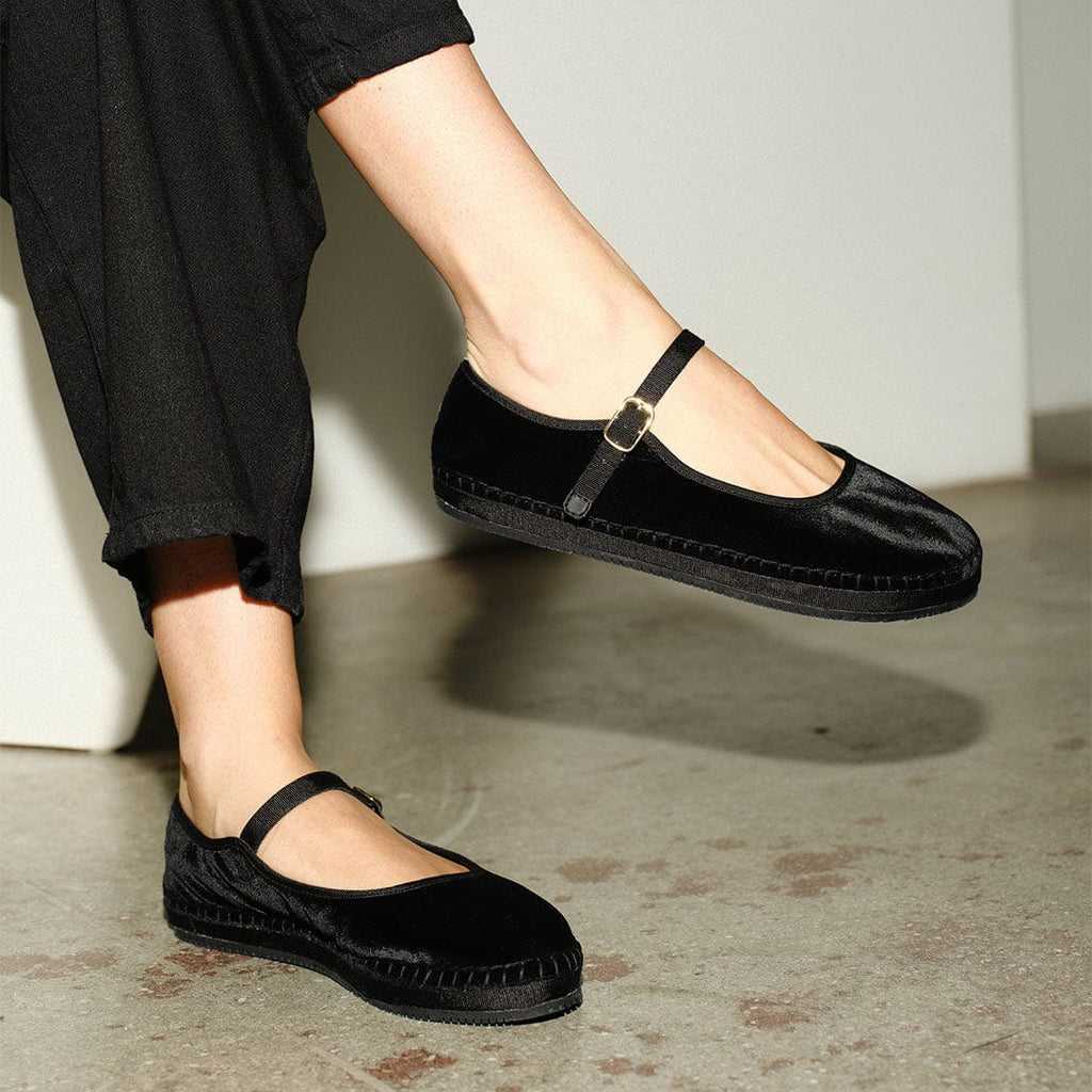 Women's Carlyle Mary Jane in Black velvet, worn with black pants, one foot raised