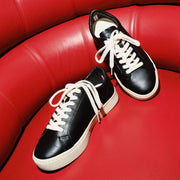Women's Diamond Cup sneaker in Black leather, pair on a red leather surface, top view