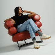 Women's Diamond Cup sneaker in Ecru leather, ecru pair worn by a woman seated in a red leather chair