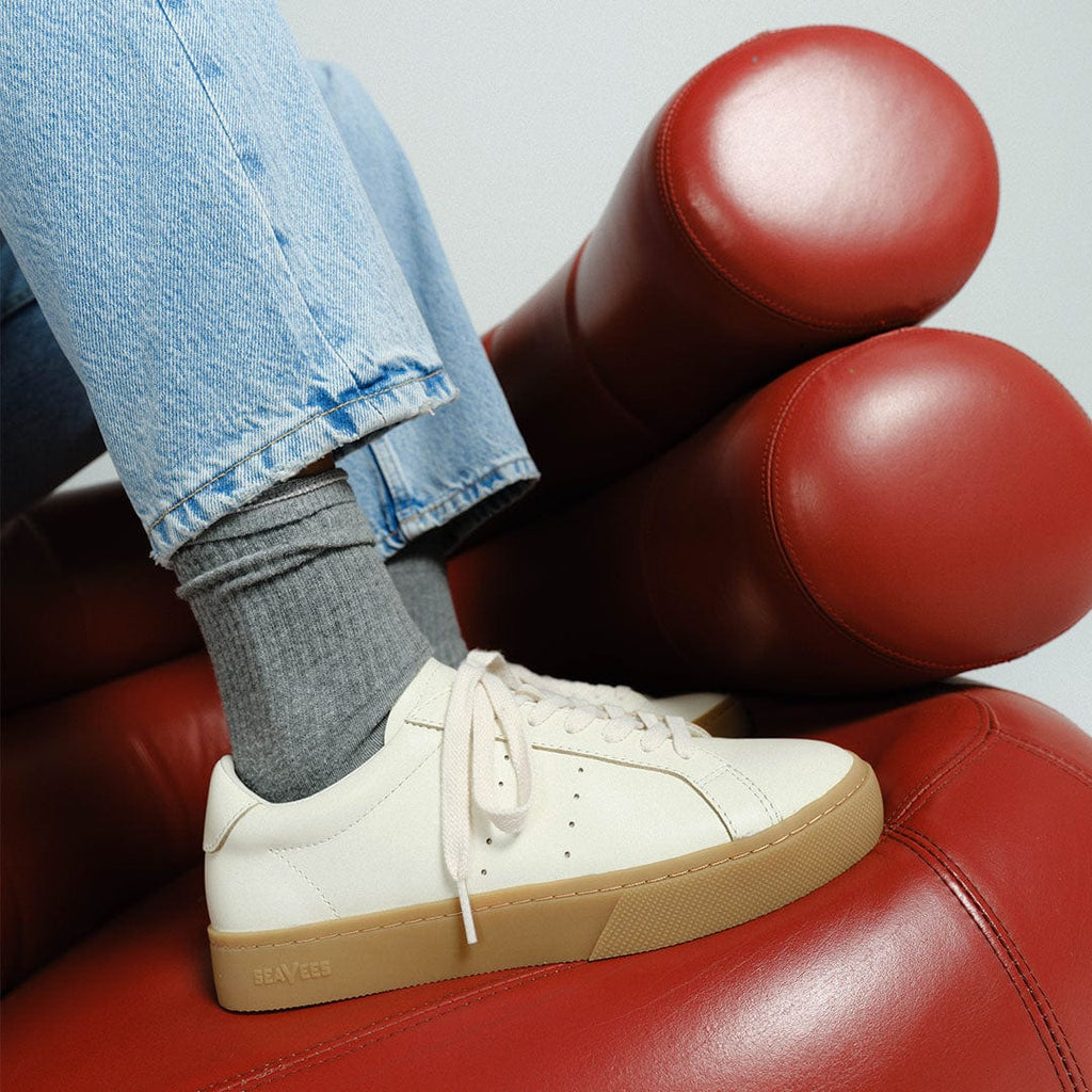 Women's Diamond Cup sneaker in Ecru leather, ecru pair worn with jeans on a red leather chair, side view