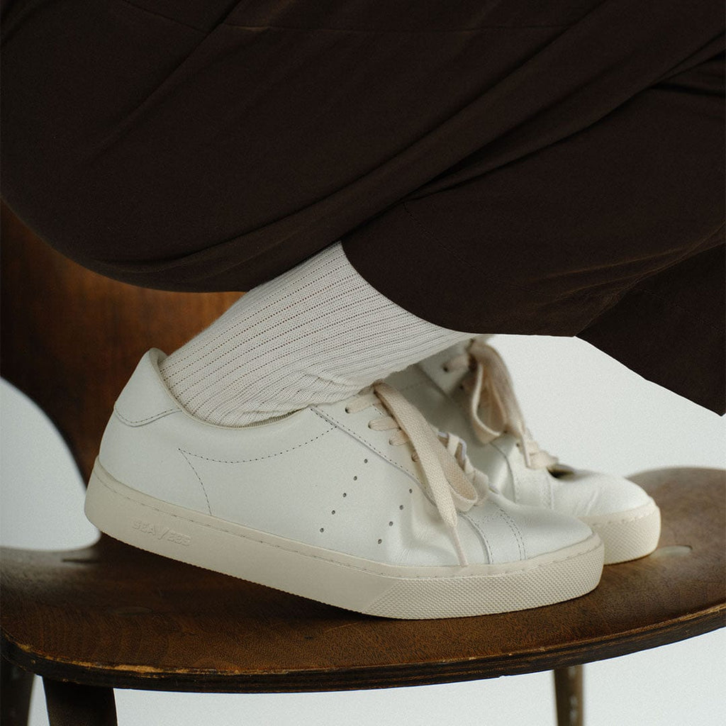 Women's Diamond Cup sneaker in White leather, worn with white socks on a wooden table, side view