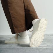 Women's Diamond Cup sneaker in White leather, worn with brown pants, sole raised