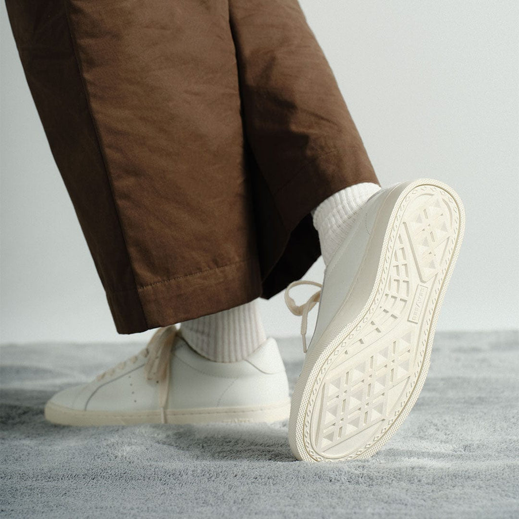 Women's Diamond Cup sneaker in White leather, worn with brown pants, sole raised