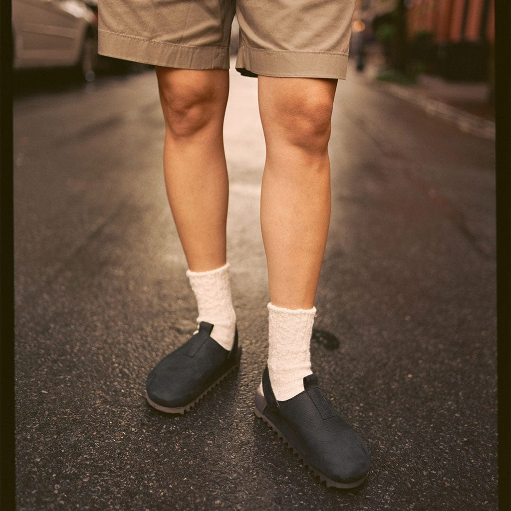 Women's Tahoe Trekker sandal in Black leather, worn with white socks and khaki shorts on a city street
