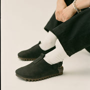 Women's Tahoe Trekker sandal in Black leather, worn with white socks and dark pants, seated, close up